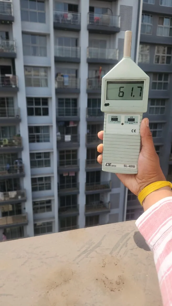 Sound-level meter displaying 61.7 with residential towers in the background